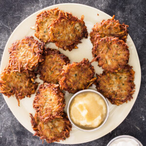 Plate of crispy Potato Latkes with a side of applesauce.