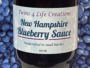 A bottle of blueberry sauce on top of blue fabric.