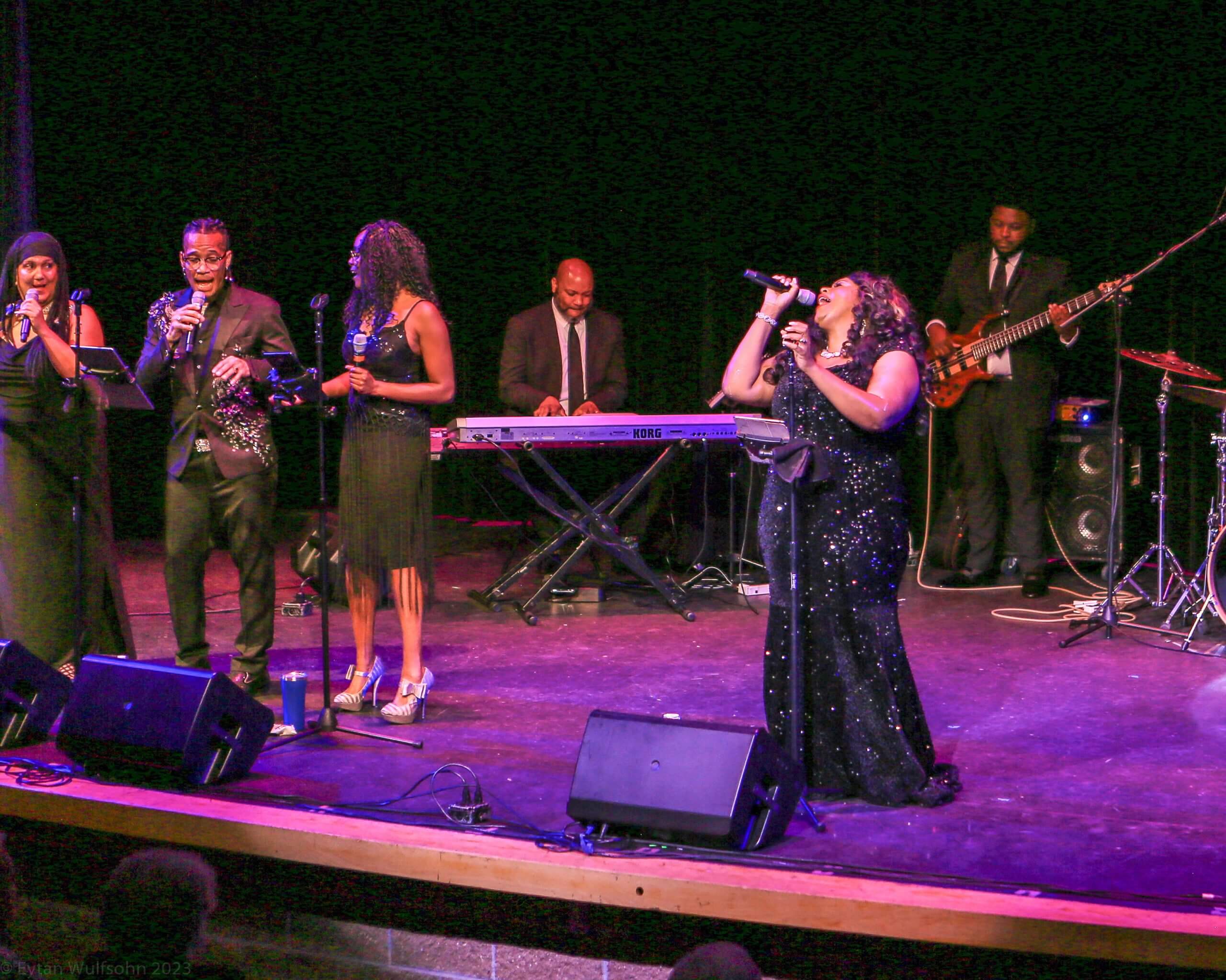 A woman singing on stage with other people.