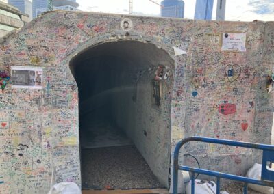 Graffiti-covered tunnel entrance with messages and drawings on its walls.