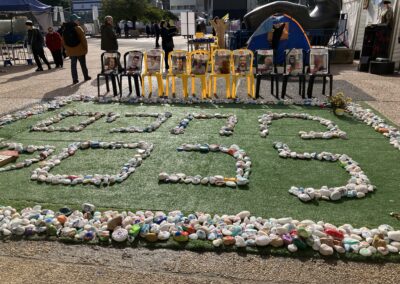 Recycling awareness display using plastic bottles to form the year "2020" on a grassy area in an outdoor setting with people nearby.