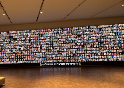 A large wall displaying an array of various video screens, each showing different images, viewed from inside a gallery.