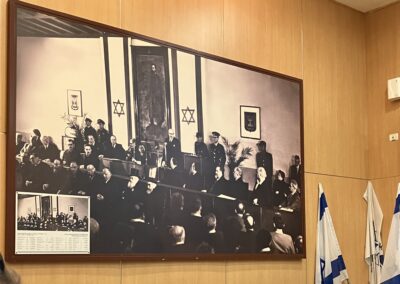 A large framed historical photograph depicting a formal gathering displayed on a wall, with israeli flags on the right.